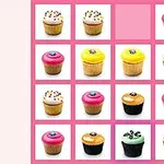 Kupcake shumëngjyrëshe të renditura në një tabelë rozë me një hapësirë bosh në katrorin e sipërm