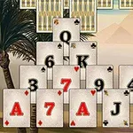 Kartat e lojës të radhitura në formë piramide me sfond palme dhe male