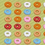 Rreshta donutsësh me ngjyra dhe zbukurime të ndryshme në një sfond jeshil