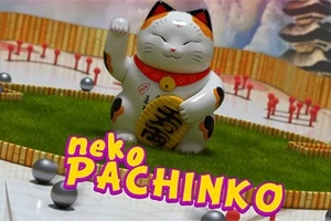 Një statujë e një mace fatlume japoneze mbi një fushë lojërash me topa metalikë dhe mbishkrimin neko pachinko në pjesën e përparme