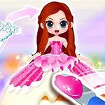 Një kukull me flokë të gjatë kafe dhe fustan rozë qëndron mbi një tortë të dekoruar, me një kurorë pastel në sfond