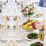 Tavolinë festive e shtruar me pjatanca, fruta të freskëta, lule dhe dekorime elegante