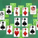 Një grup letrash lojë me figura dhe numra të ndryshëm, të vendosura në një formacion të veçantë mbi një sfond jeshil