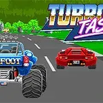 Një makinë blu me rrota të mëdha dhe një makinë sportive të kuqe garojnë në një rrugë me pemë, me logon TURBO TASTIC sipër